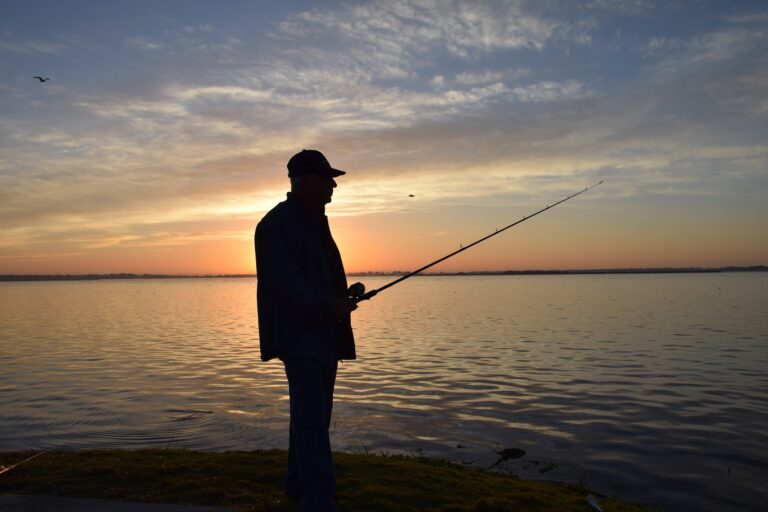 A silhouette of a man fishing on a lake