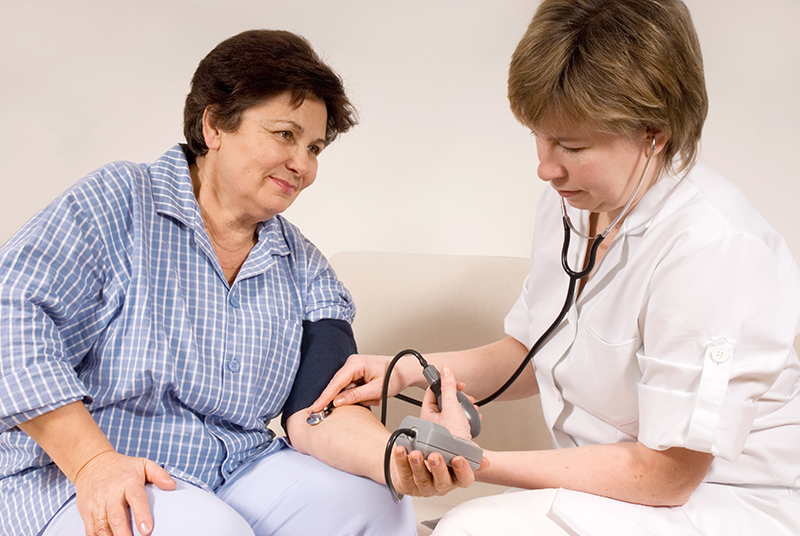 A female nurse or doctor taking the blood pressure of a woman.